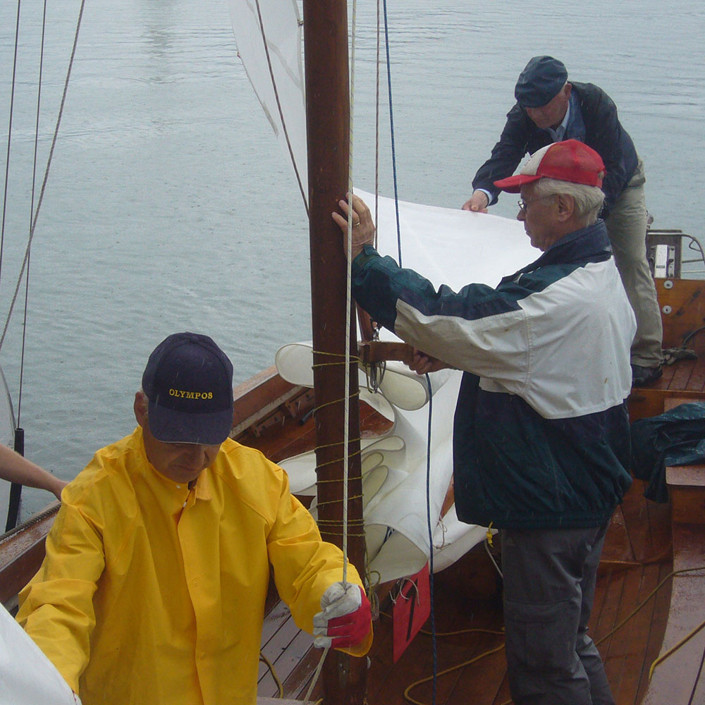 Three older men makes preparations on a sailing boat